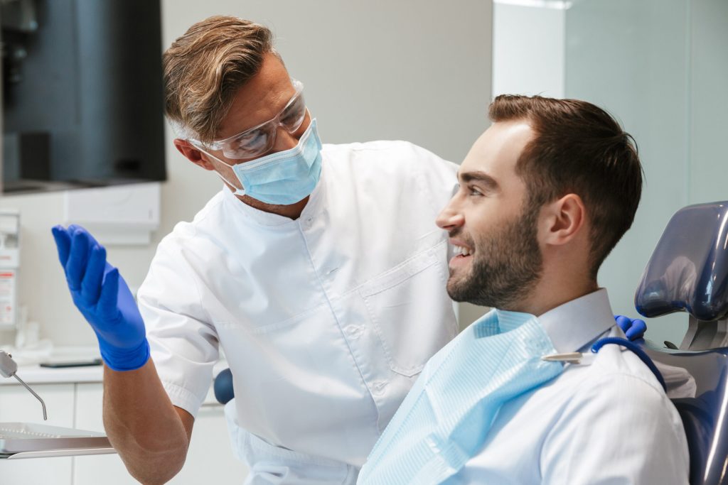 Handsome happy young man sitting in medical dentist center.